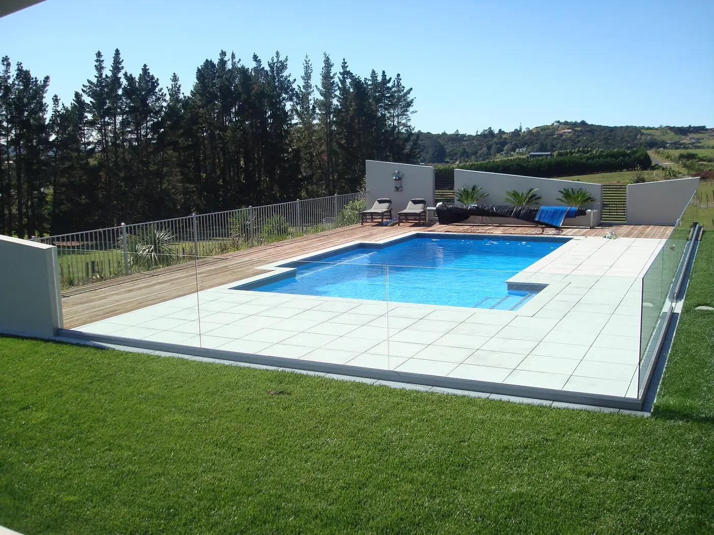 Pool with glass fencing and timber deck by Custom Decks and Fences